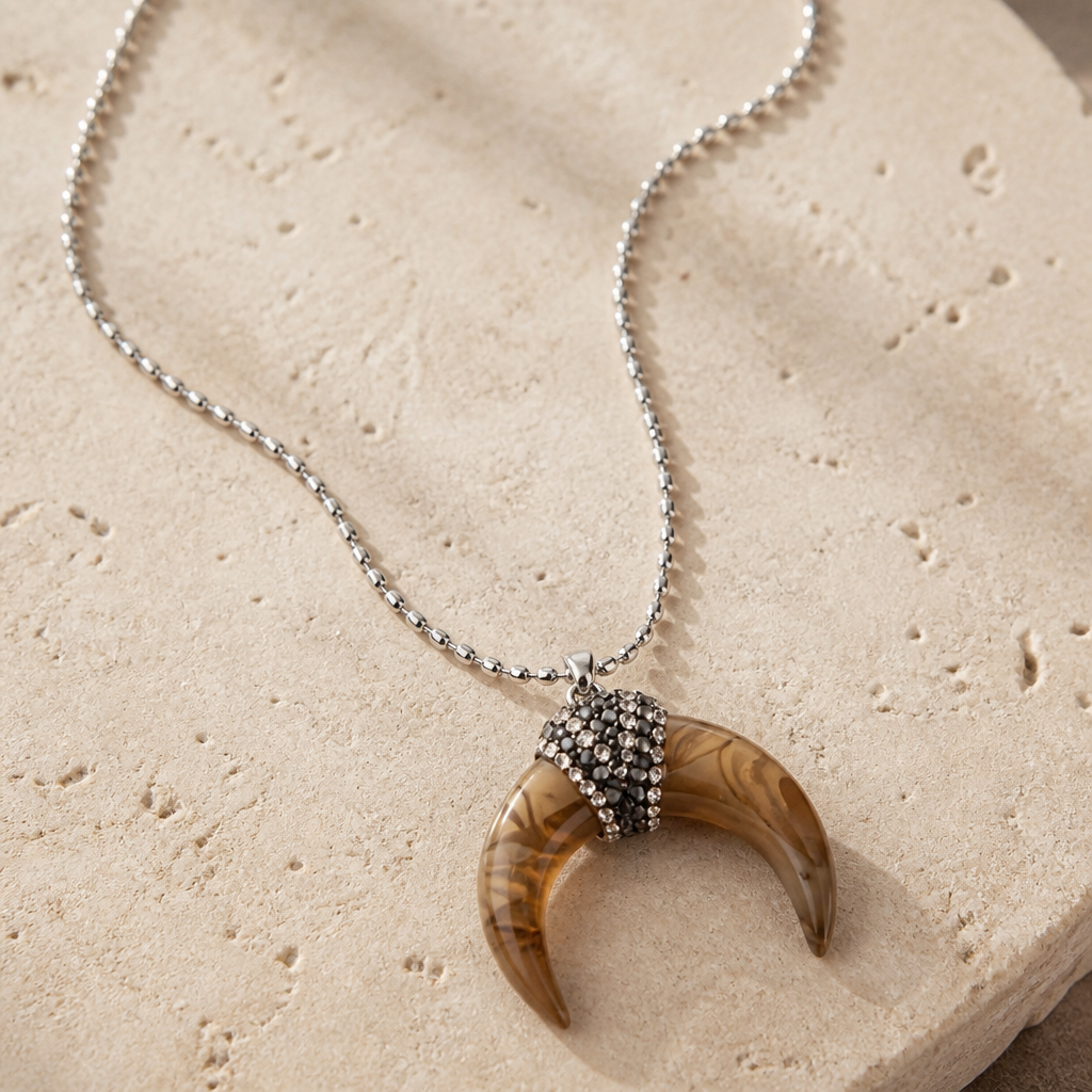 RHINESTONE CRESCENT HORN PENDANT ON A SILVER-TONE STAINLESS STEEL CHAIN.